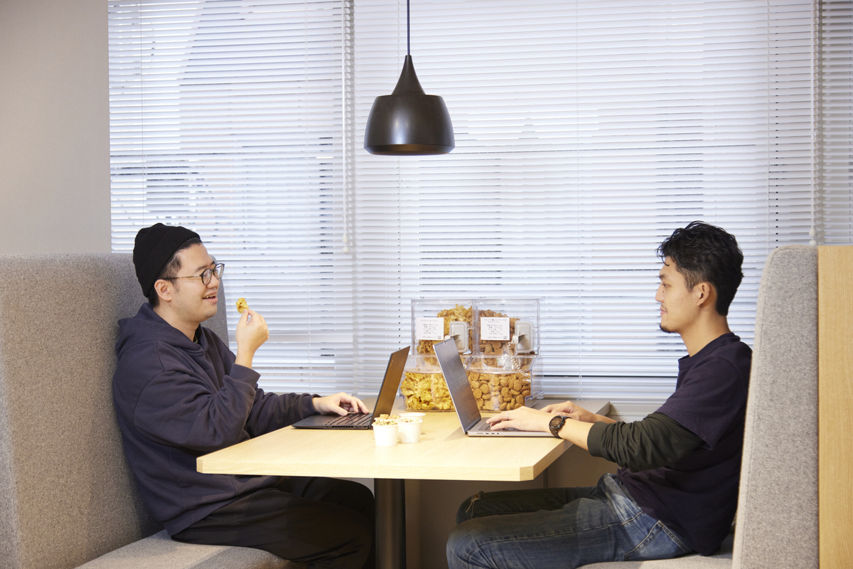 社内休憩スペースで軽食をつまみながら談笑する従業員