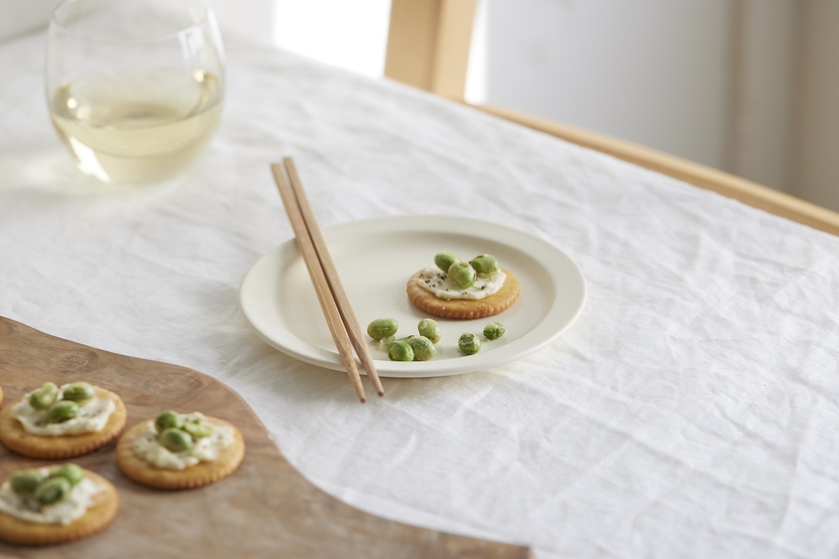 お皿に盛られた枝豆のおかずと、グラスなどが並ぶテーブル